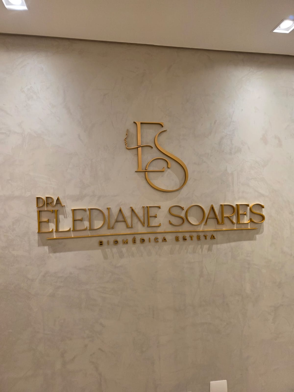 Marca Dra. Elediane Soares em letras douradas aplicadas na parede